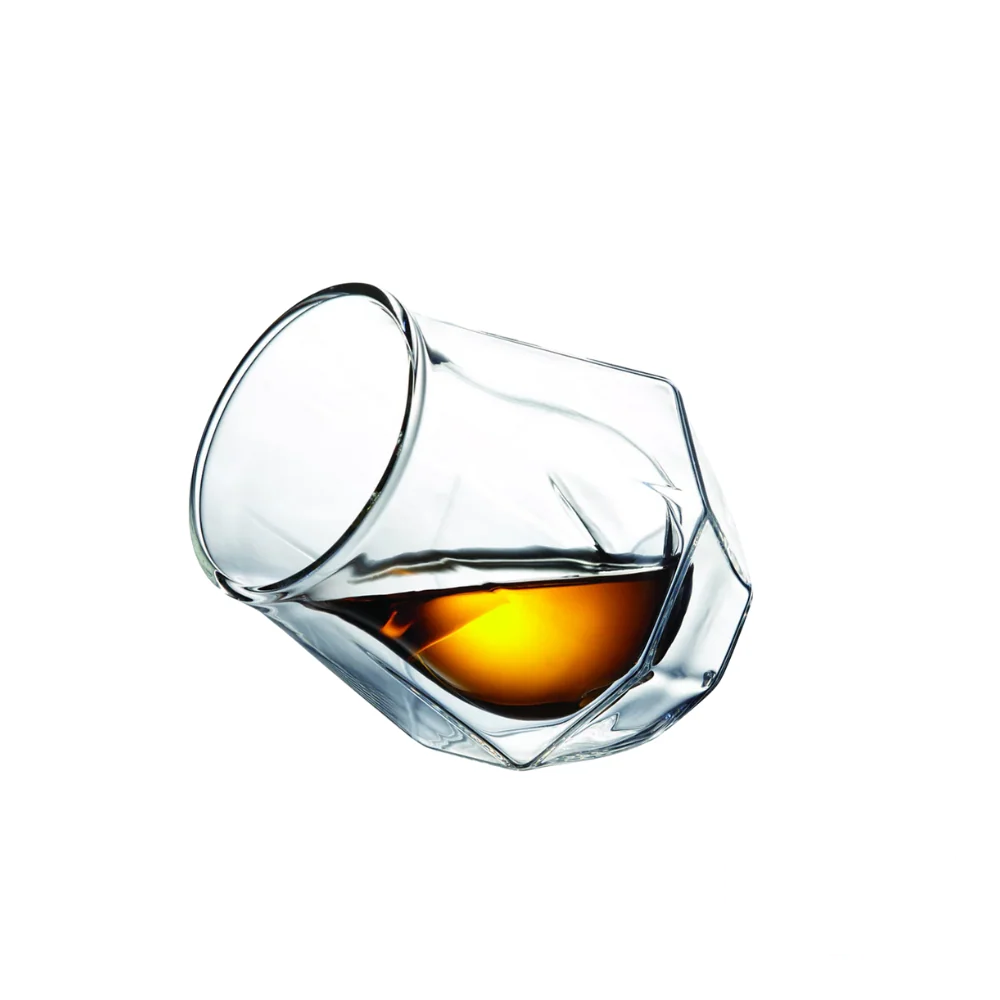 A Diamond Double Wall Whisky Glass tilted to the side, partially filled with golden whisky, highlighting its sleek, geometric design and double-wall insulation.