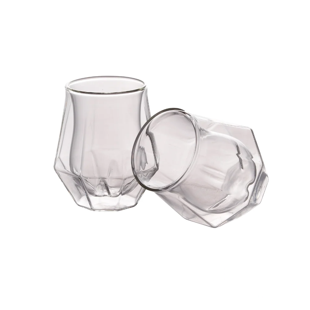 A set of two Diamond Double Wall Whisky Glasses, one standing upright and the other resting on its side, showcasing their unique faceted design and modern double-wall construction.