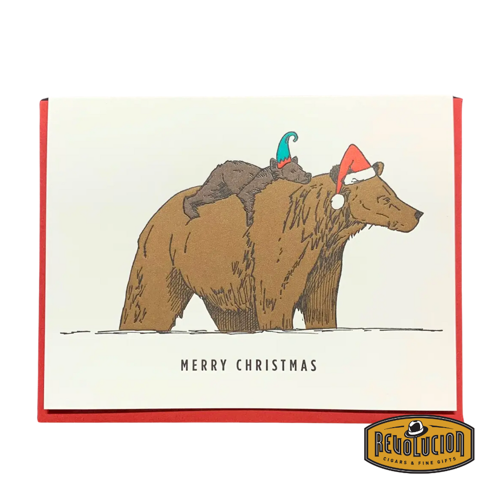 Two grizzly bears wearing festive hats, with a small bear cub asleep on the bigger bear's back, and the caption “Merry Christmas.”