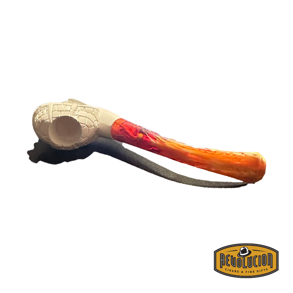 Top view of a Meerschaum pipe featuring a cream-colored bowl with a carved face of a man wearing a helmet. The stem is a vibrant red marbled color, and the pipe is resting on a dark surface.