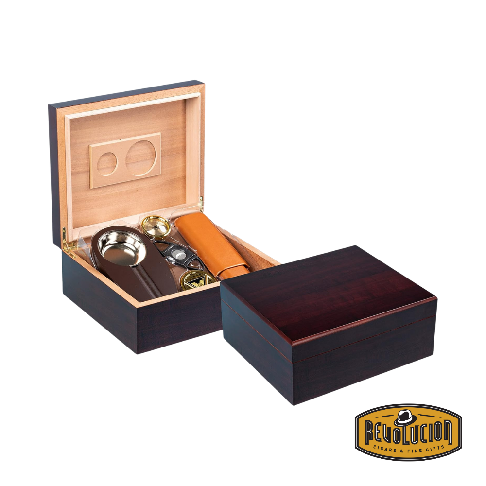 A luxurious wooden cigar humidor, partially opened, revealing a well-organized interior with premium cigar accessories. The humidor is crafted with a rich wood finish and a cedar-lined interior. The Revolucion Cigars & Fine Gifts logo is present in the bottom right corner.