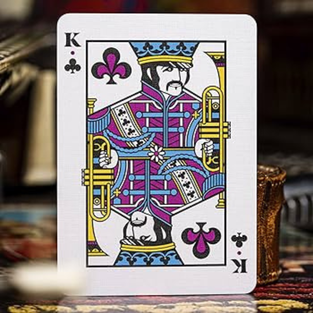 King of Clubs card from Theory 11 Beatles Playing Cards Pink Edition, illustrated in a colorful Sgt. Pepper style with a trumpet.