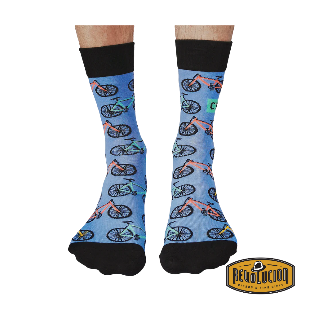 Front view of blue socks with colorful bicycle graphics and black cuffs and toes. The socks are branded with the Revolucion Cigars & Fine Gifts logo.