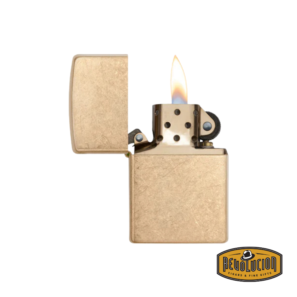 An open Zippo Armor Tumbled Brass Lighter showcasing its rugged brass finish and windproof flame mechanism. The durable Armor case enhances its premium feel. The Revolucion Cigars & Fine Gifts logo is visible in the corner.