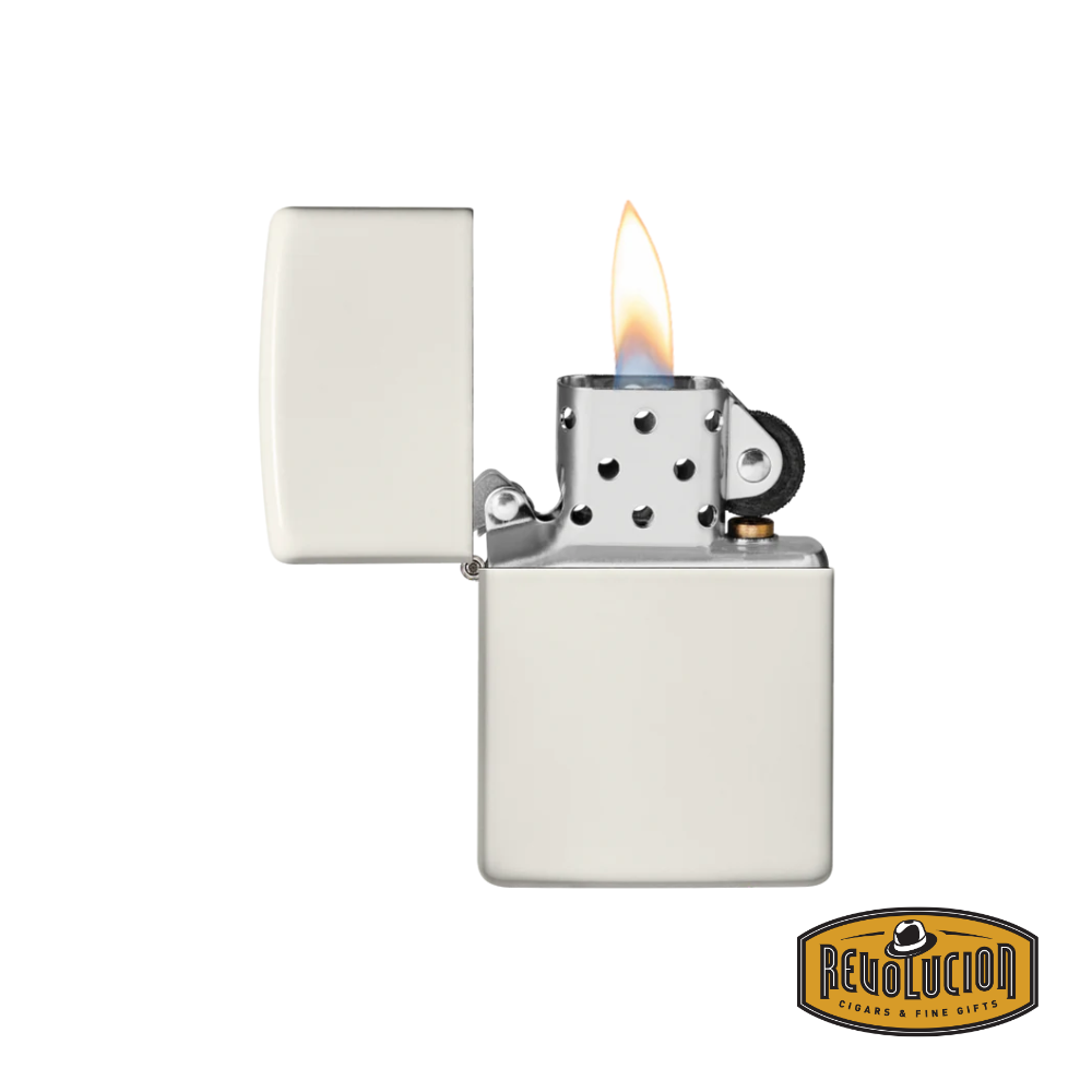 Zippo Glow In The Dark Matte lighter, opened and ignited, revealing its signature windproof flame. The Revolucion Cigars & Fine Gifts logo is visible in the corner.