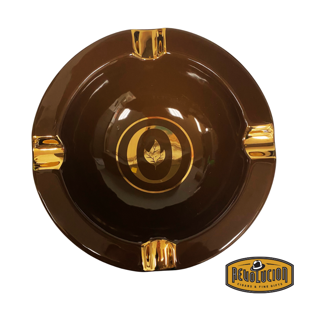 Top view of the Oliva Round Ashtray in Gold/Brown, showcasing its luxurious finish, four cigar grooves, and iconic Oliva logo, displayed with the Revolucion Cigars & Fine Gifts logo.
