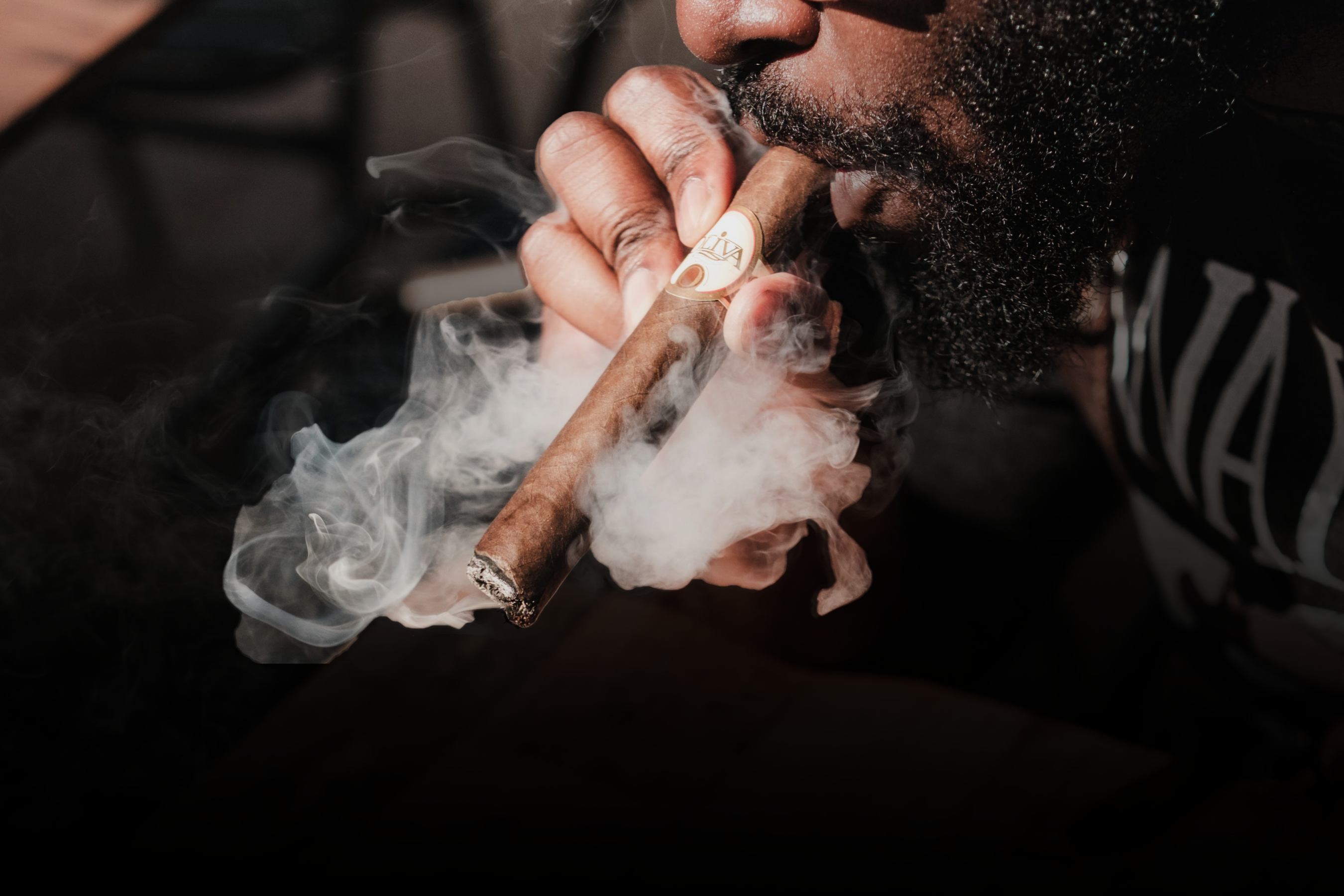 Person at Revolucion smoking a Olivia cigar with smoke visible. Available online - find the best prices on cigars and more in Canada