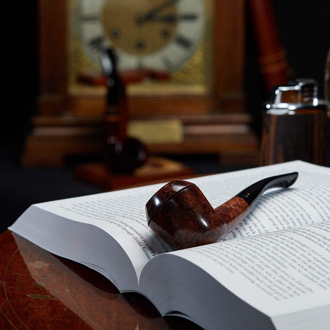 Brigham Algonquin #26 Smoking Pipe resting on a book, showcasing its elegant design and craftsmanship.