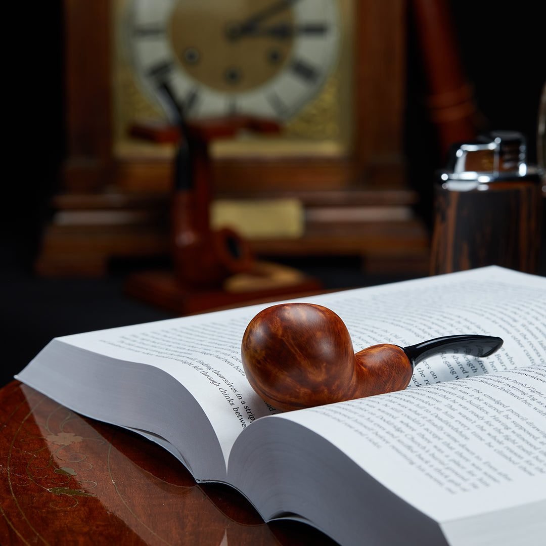 Chacom Reverse Calabash Smoking Pipe resting on a book, showcasing its unique design and smooth briar finish.