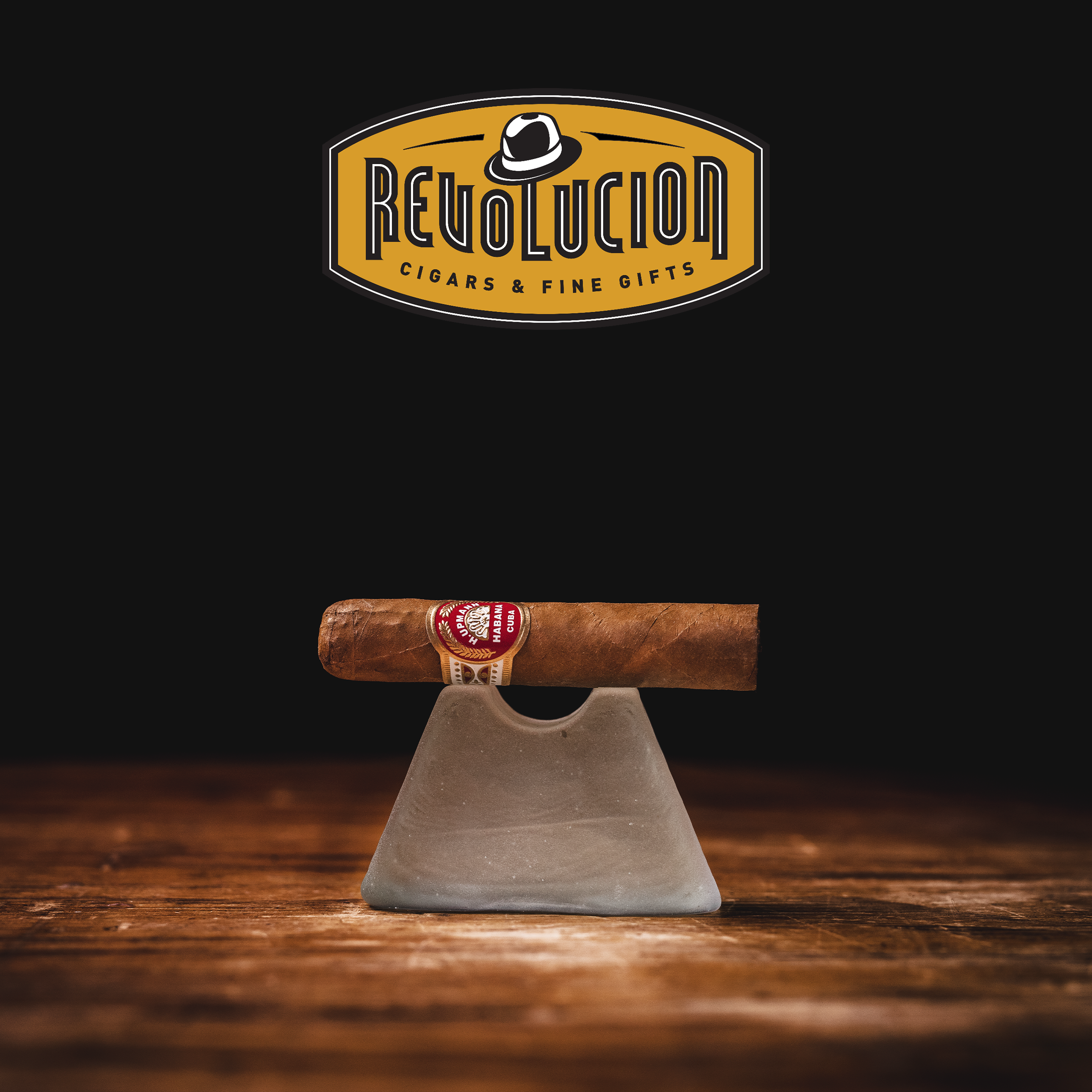 H. Upmann Half Corona Cuban cigar with a red and gold band, resting on a dark background.