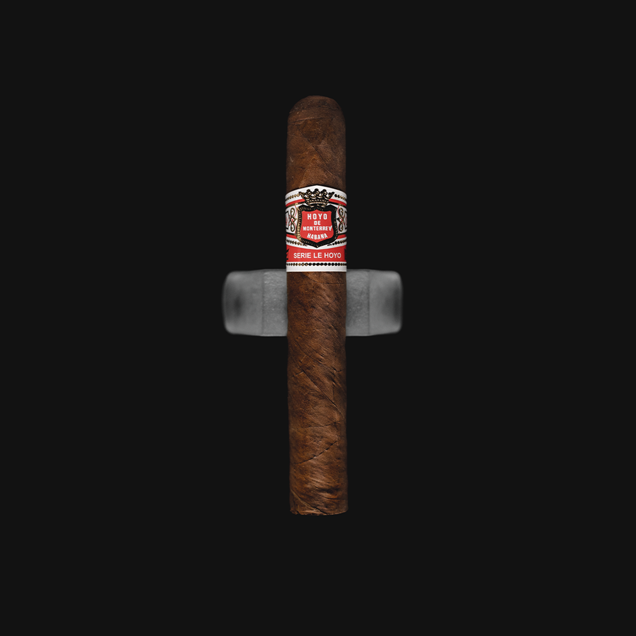 Hoyo de Monterrey San Juan cigar with a red and white band, placed on a Dark background.