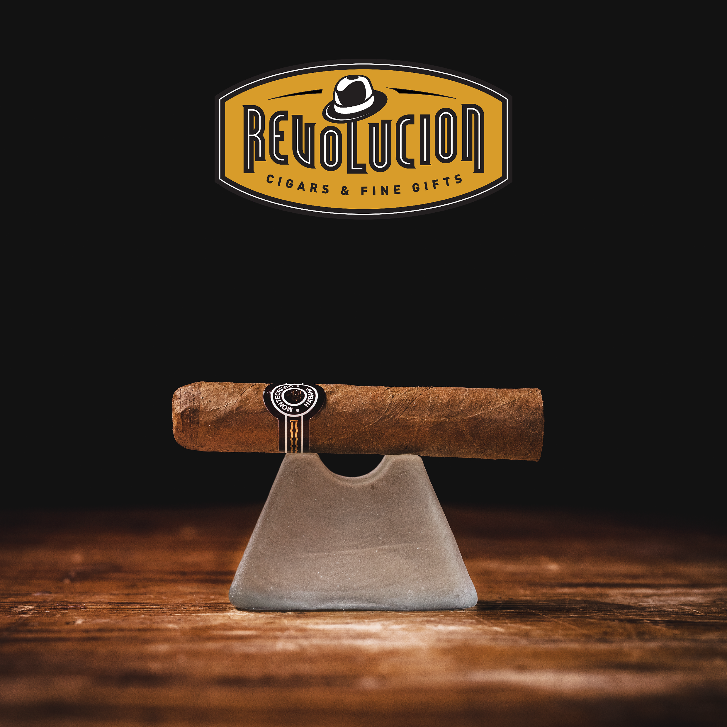 Montecristo Petit Edmundo Cuban cigar with a brown and white band, placed on a glass object with a dark background.