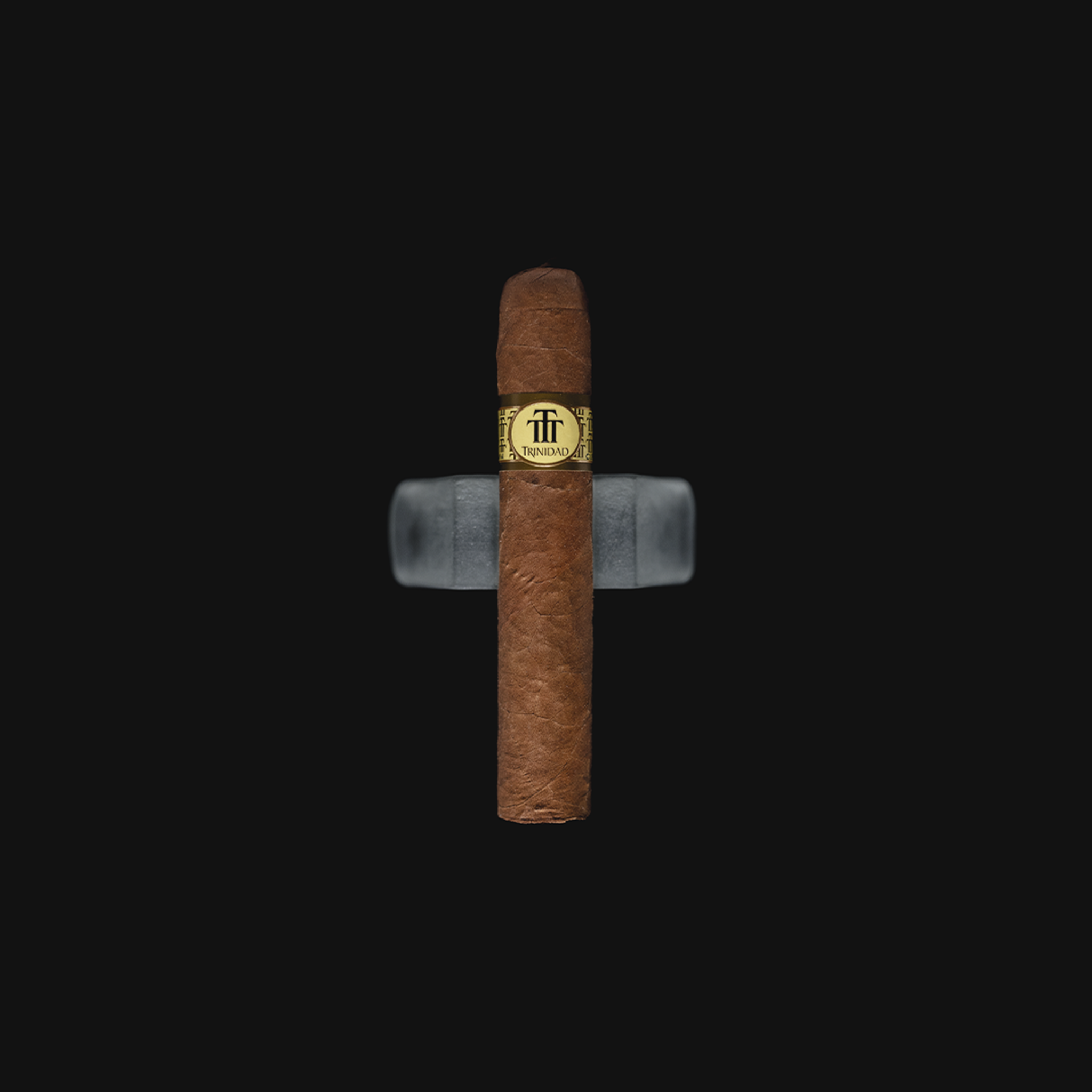 Trinidad Media Luna Cuban cigar placed on dark background, showcasing its golden band and signature pigtail cap.