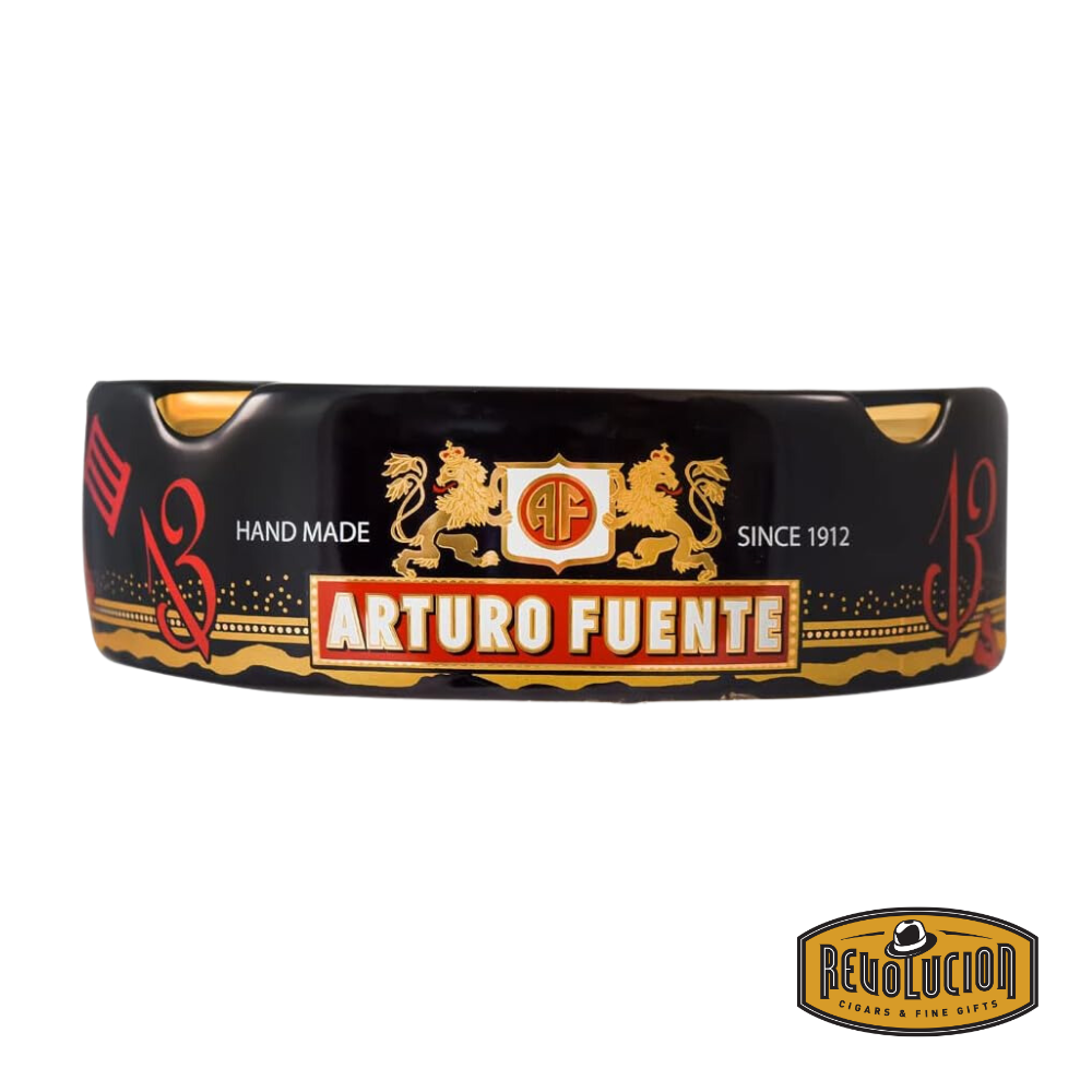 Arturo Fuente 'Journey Through Time' Ashtray in Black, featuring a vibrant design with four gold cigar grooves and iconic Arturo Fuente artwork, displayed with the Revolucion Cigars & Fine Gifts logo.