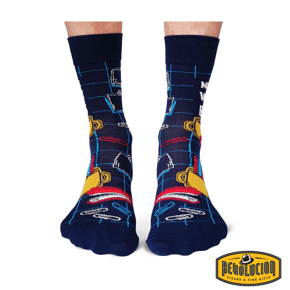 Front view of navy blue socks with office-themed graphics, including briefcases, coffee cups, and notebooks. The socks feature black cuffs and toes and are branded with the Revolucion Cigars &amp; Fine Gifts logo