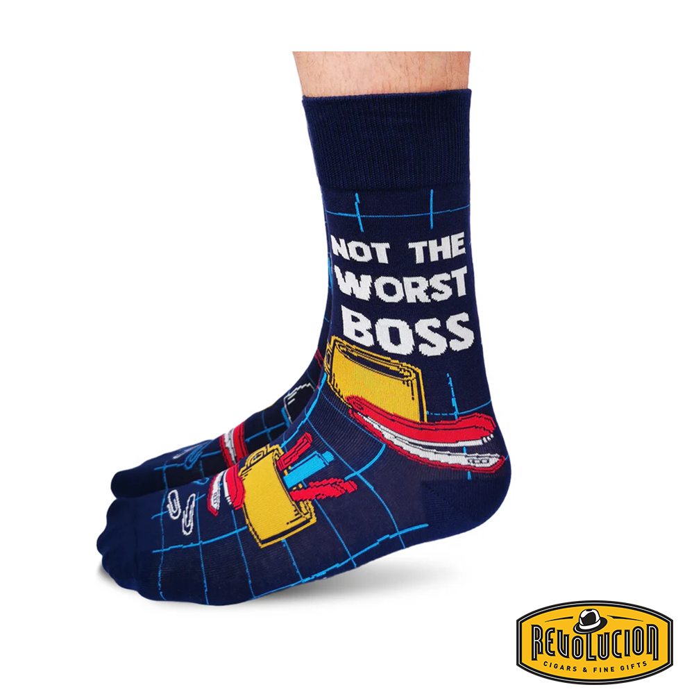 Front view of navy blue socks with office-themed graphics, including briefcases, coffee cups, and notebooks. The socks feature black cuffs and toes and are branded with the Revolucion Cigars & Fine Gifts logo