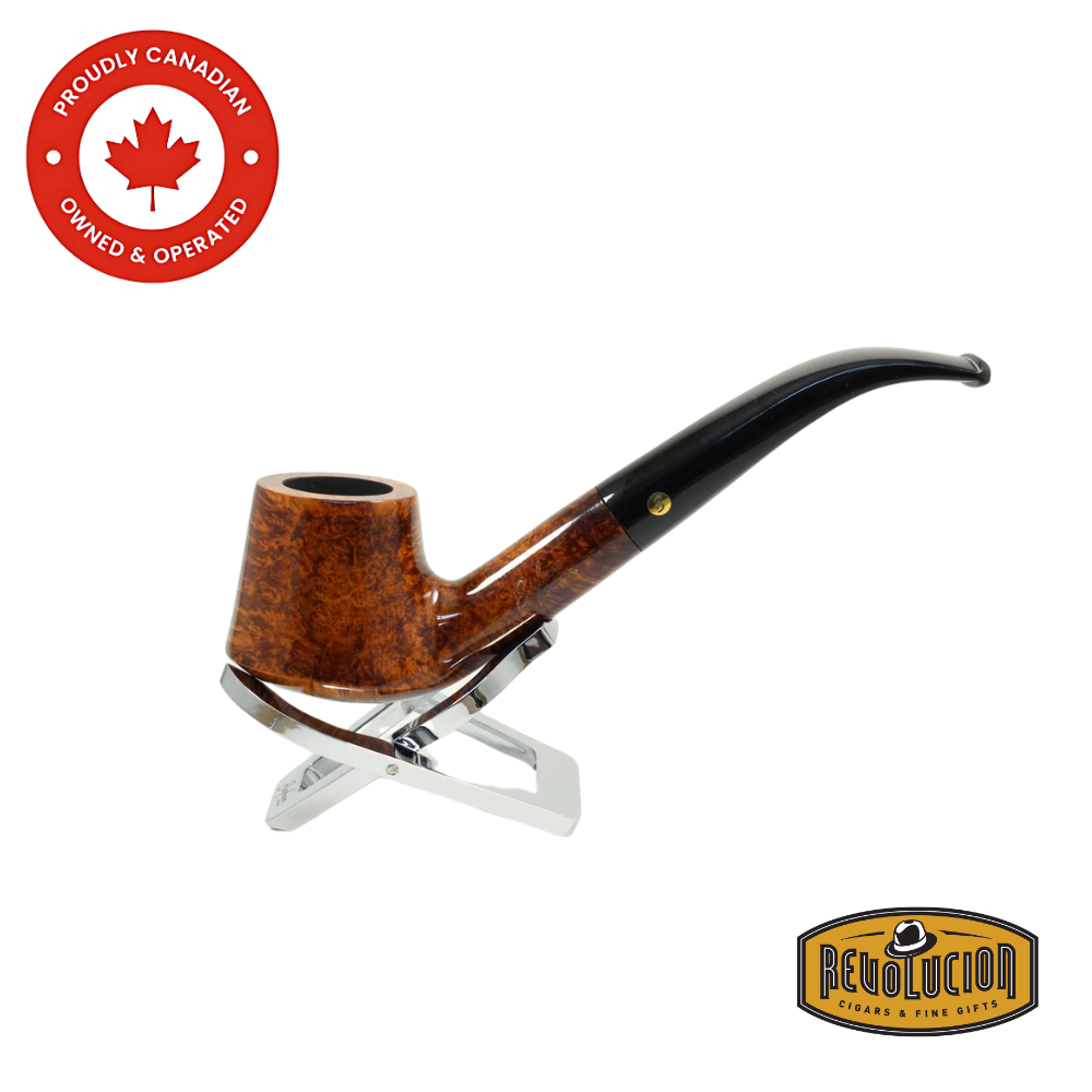 Brigham Klondike #84 Smoking Pipe – a polished bent pipe made of high-grade briar with a vibrant amber-brown grain and a black acrylic stem, shown resting on a chrome pipe stand with Canadian and Revolucion branding.