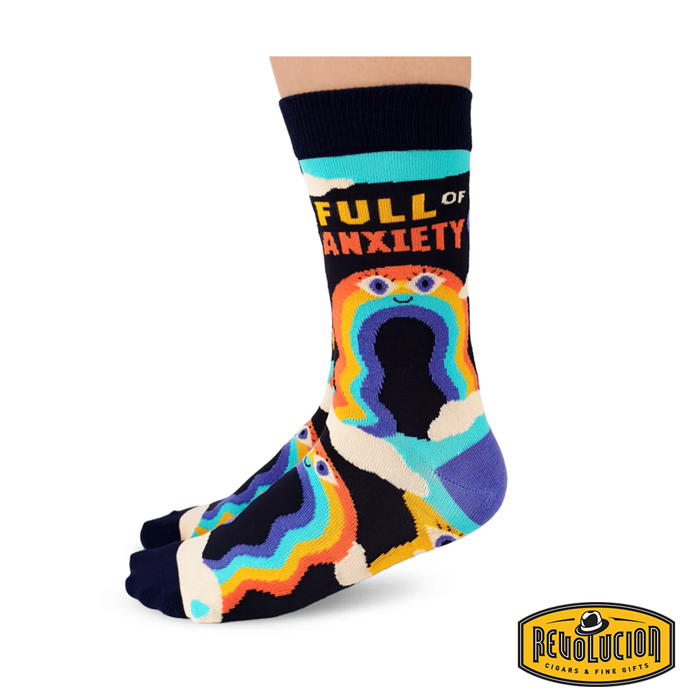 Side view of colorful socks featuring a whimsical design with rainbows, clouds, and a smiling face. The socks display the phrase 'Full of Anxiety' and have black cuffs and toes.