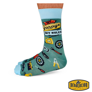 Side view of green socks with light blue cuffs and toes, featuring garage-themed graphics and the phrase 'My Garage My Rules.' The socks are branded with the Revolucion Cigars & Fine Gifts logo