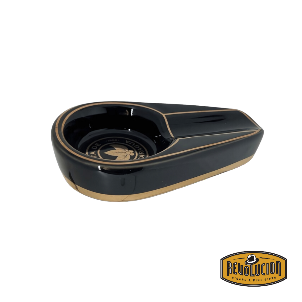 Joya de Nicaragua Mini Ashtray in sleek black with gold accents, featuring a single cigar rest and deep basin, displayed with the Revolucion Cigars & Fine Gifts logo.