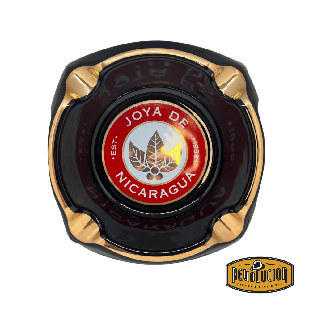 op view of the Joya de Nicaragua Gift Ashtray, featuring a bold black design with gold and red accents, and the iconic Joya de Nicaragua logo, displayed with the Revolucion Cigars &amp; Fine Gifts logo.