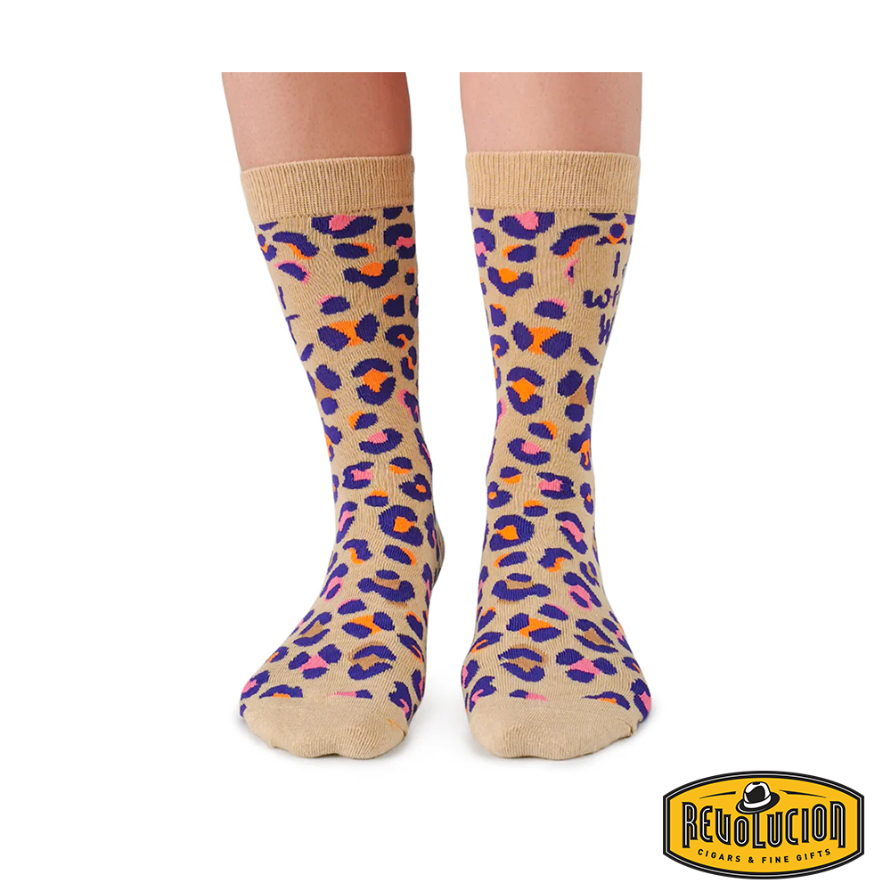 Front view of beige socks with vibrant purple, pink, and orange leopard print pattern. Socks feature the phrase &#39;I do what I want&#39; and are branded with the Revolucion Cigars &amp; Fine Gifts logo