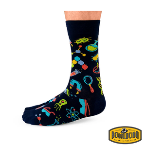 Side view of black socks featuring vibrant science-themed graphics including test tubes, molecules, and magnifying glasses. The socks are branded with the Revolucion Cigars & Fine Gifts logo