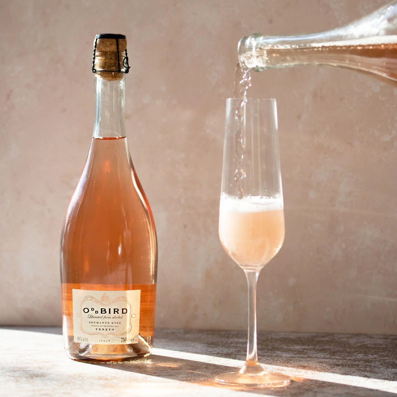Oddbird Spumante Rose Non-Alcoholic 750 ml bottle alongside a glass, emphasizing the sophisticated presentation of the sparkling wine.