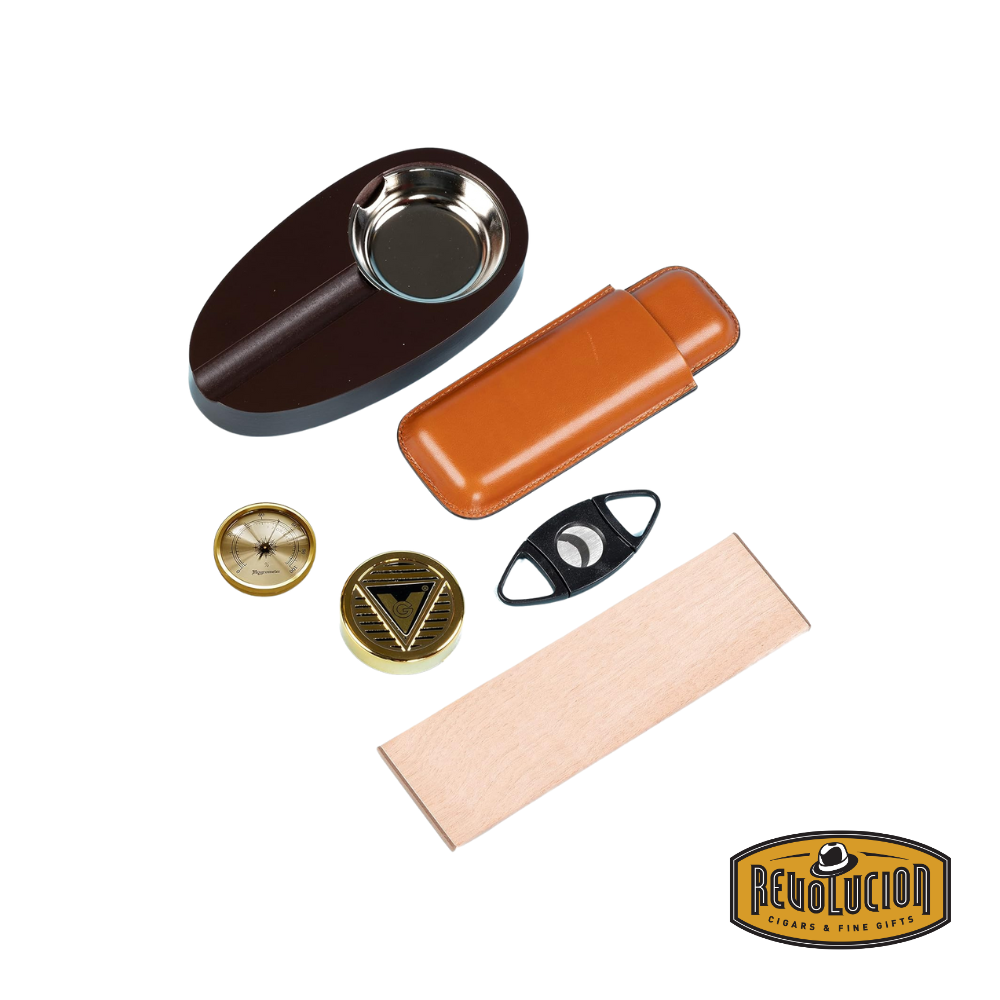 A collection of cigar accessories, including a wooden ashtray with a metal bowl, a brown leather cigar case, a black double-blade cutter, a gold-tone hygrometer, a humidifier, and a wooden divider, displayed separately. The Revolucion Cigars & Fine Gifts logo is visible in the bottom right corner.