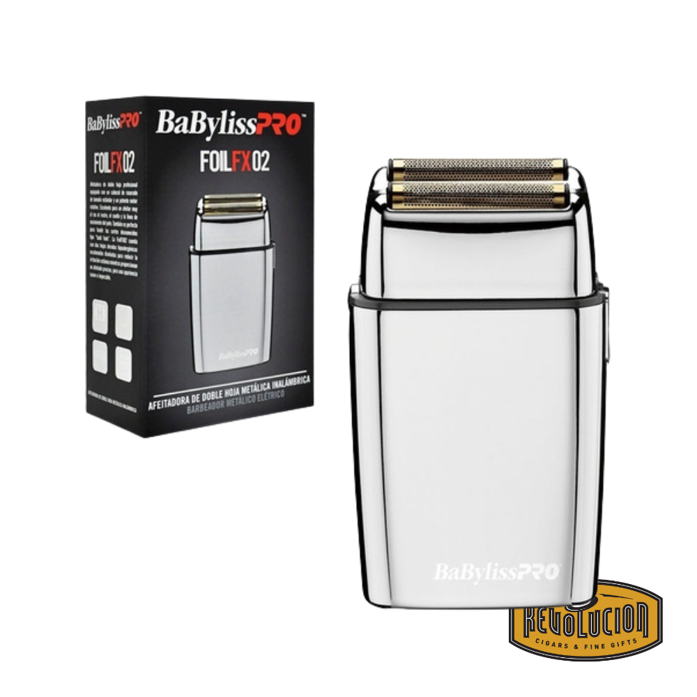 BaBylissPRO FOILFX02 double foil shaver in polished metal finish displayed next to its original black packaging, highlighting the sleek professional design and the Revolucion Cigars & Fine Gifts logo.