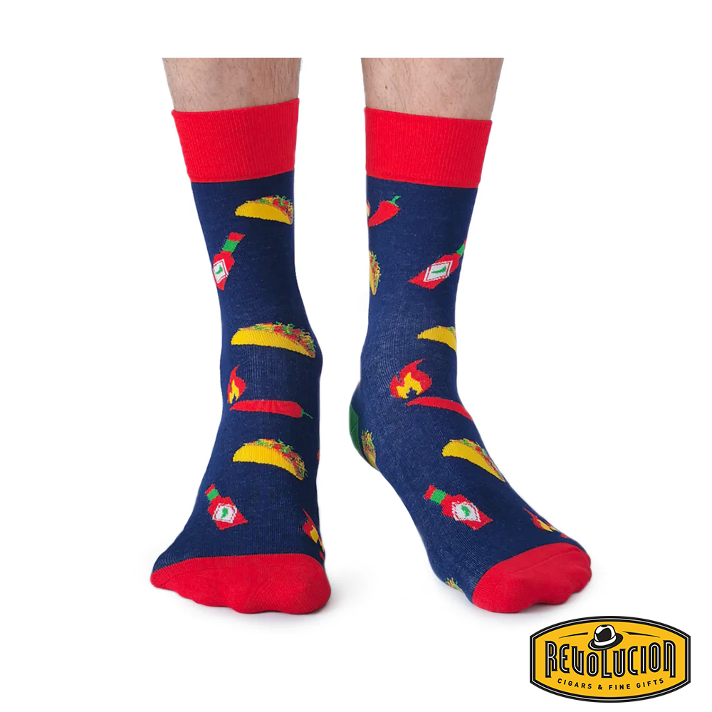 Front view of blue socks featuring taco, hot sauce bottle, and chili pepper graphics. Socks have red cuffs and toes, branded with the Revolucion Cigars &amp; Fine Gifts logo