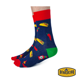 Side view of blue socks with detailed taco, hot sauce bottle, and chili pepper graphics. Socks have red cuffs, green heels, and red toes, branded with the Revolucion Cigars & Fine Gifts logo