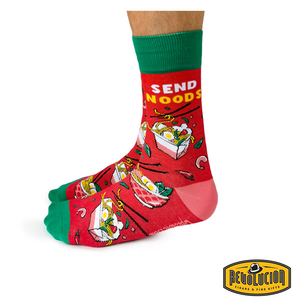 Side view of red socks featuring playful noodle graphics and the phrase 'Send Noods' in bold yellow letters. The socks have green cuffs, green toes, and pink heels, branded with the Revolucion Cigars & Fine Gifts logo