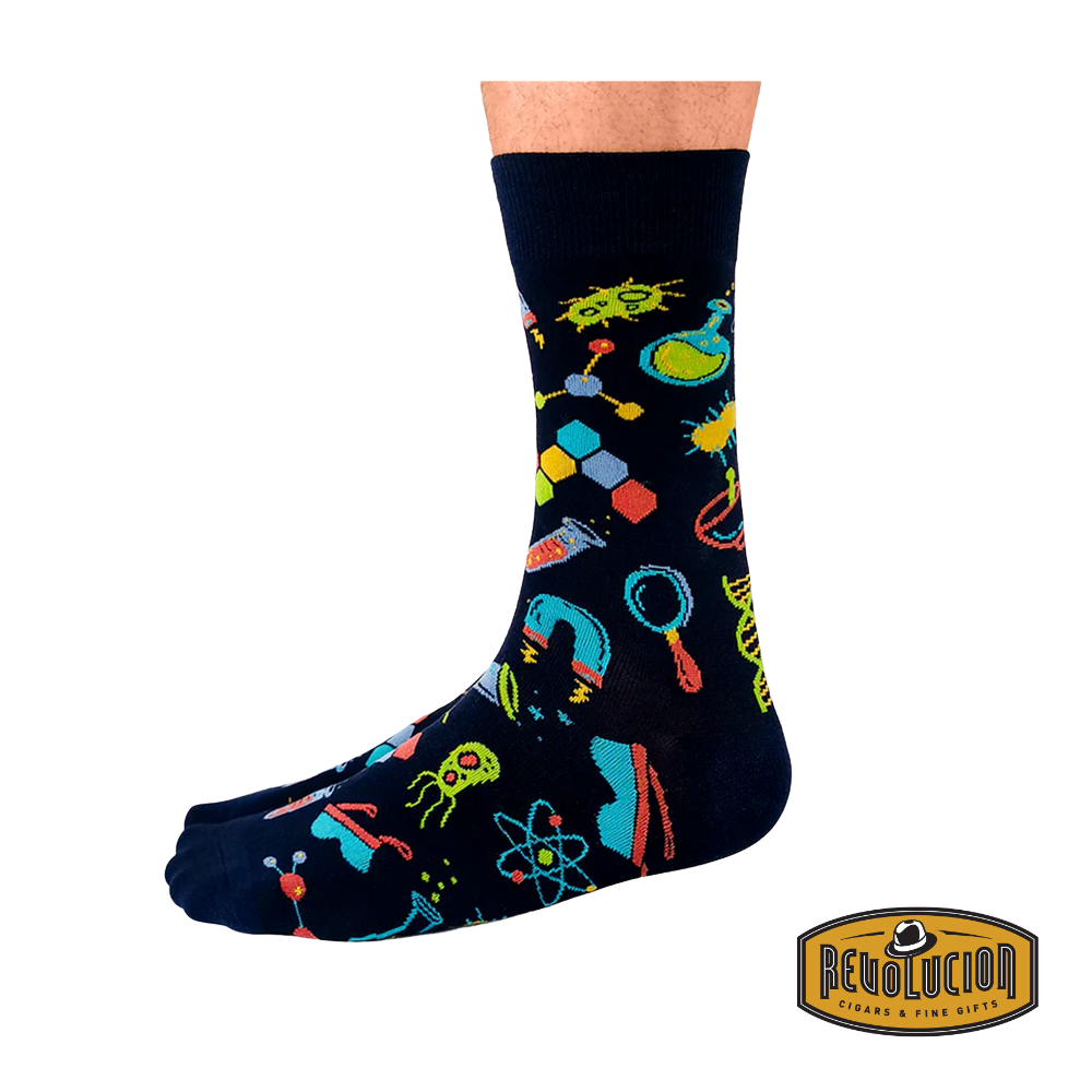 Side view of black socks featuring vibrant science-themed graphics including test tubes, molecules, and magnifying glasses. The socks are branded with the Revolucion Cigars & Fine Gifts logo.