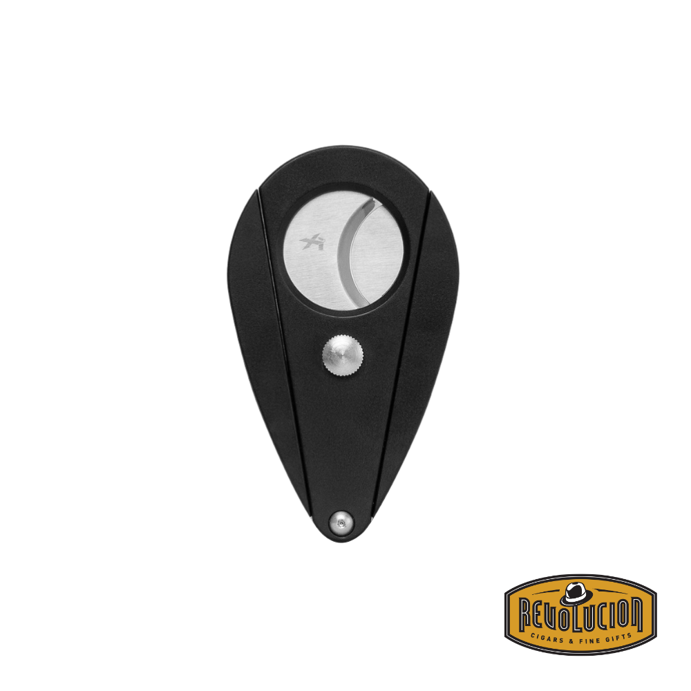 Xikar Xi2 cigar cutter in black with a closed teardrop shape, featuring stainless steel blades and a central locking mechanism. The Revolucion Cigars & Fine Gifts logo is visible in the bottom right corner.