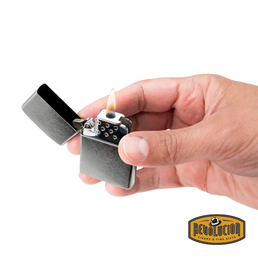 A hand holding the Zippo yellow flame lighter insert while igniting a soft, candle-like flame.