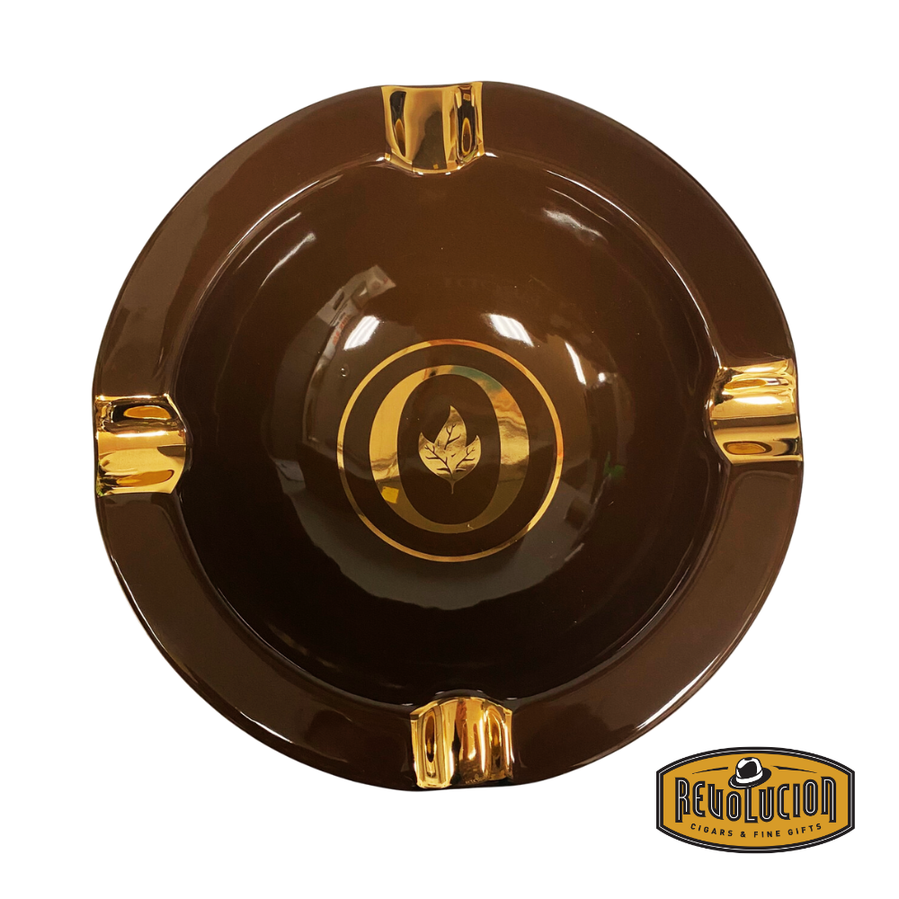 Oliva Round Ashtray in Gold/Brown, featuring a rich brown finish with gold accents, four cigar grooves, and the iconic Oliva logo, displayed with a cigar and the Revolucion Cigars & Fine Gifts logo.