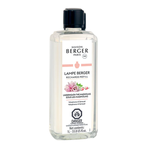 A 1 liter bottle of Lampe Berger Underneath the Magnolias fragrance oil, featuring a label with the product name and branding. The bottle is a translucent frosted color with a wide base, a narrow neck, and a black cap. 