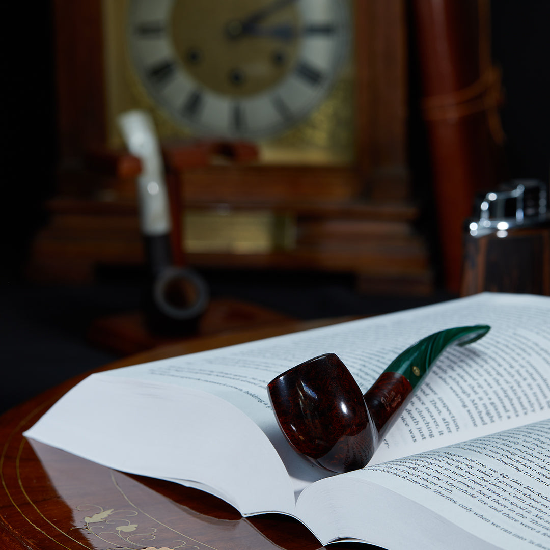 Brigham Heritage #47 Smoking Pipe resting elegantly on an open book, showcasing its classic design and warm wood grain in a lifestyle setting.