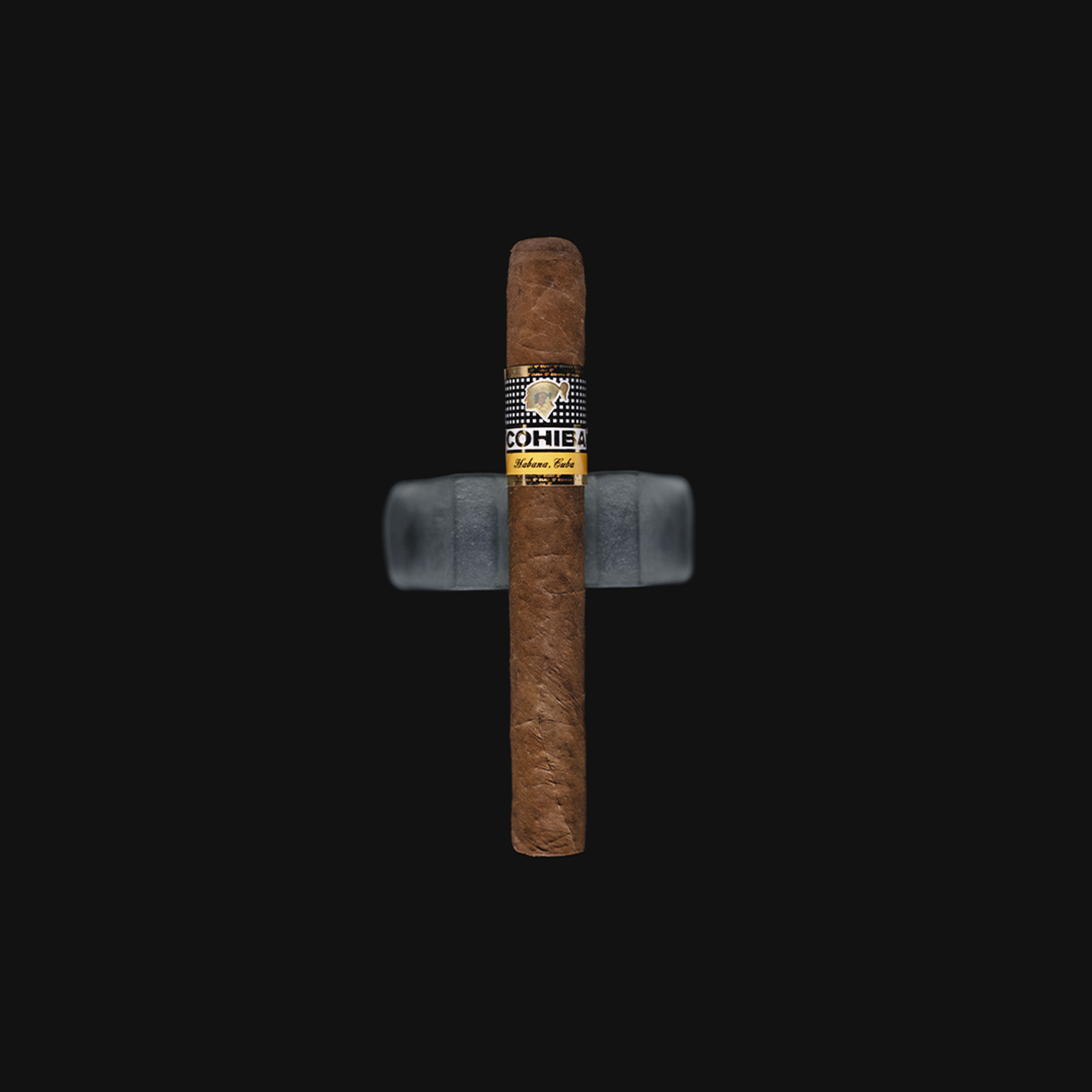 Cohiba Siglo II Cuban cigar with a golden yellow band, resting on a dark background.