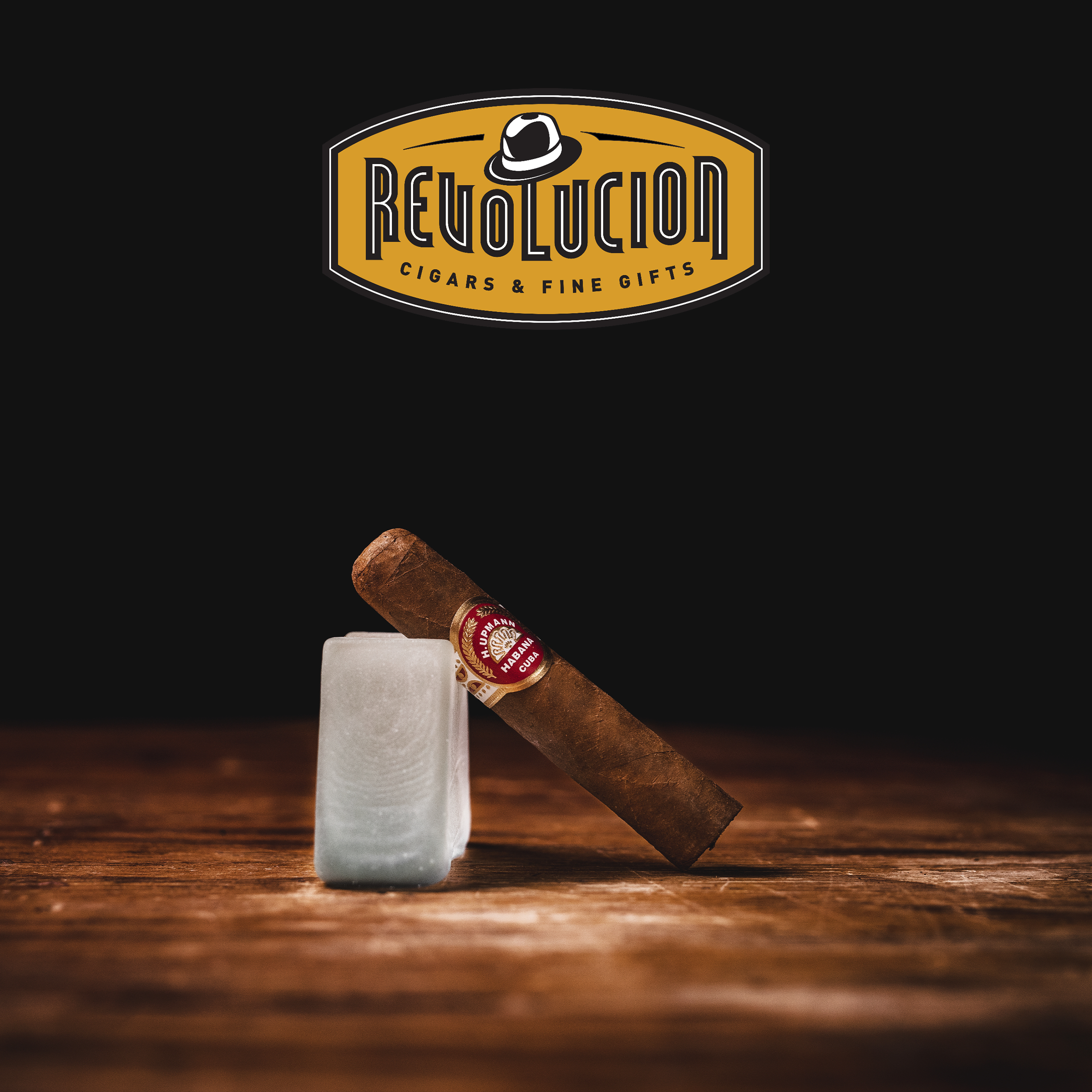 H. Upmann Half Corona Cuban cigar with a red and gold band, resting on a dark background.