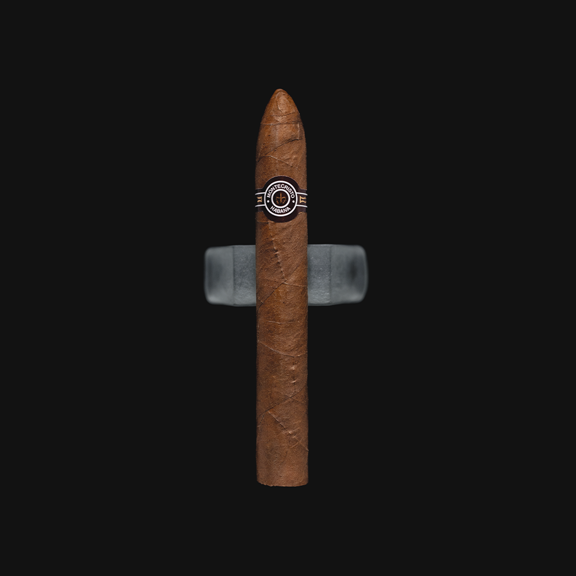 Montecristo No.2 Cuban torpedo cigar with a brown and white band, placed on a dark background.