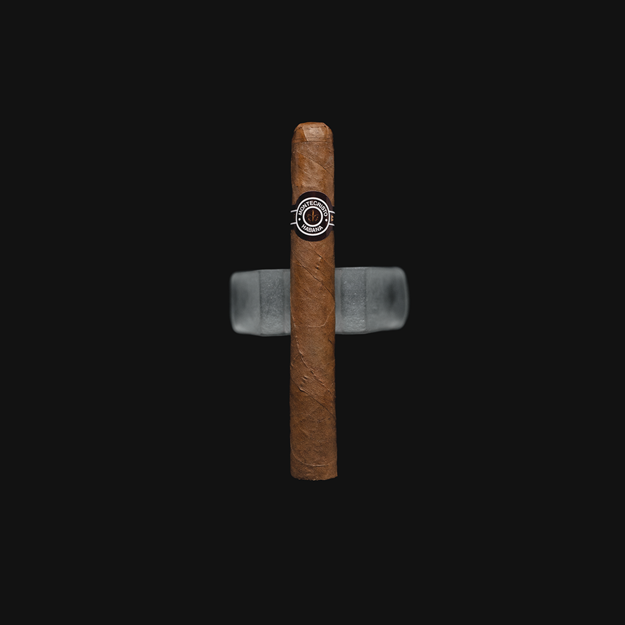 Montecristo No.4 Cuban cigar with a brown and white band, resting on a dark background.