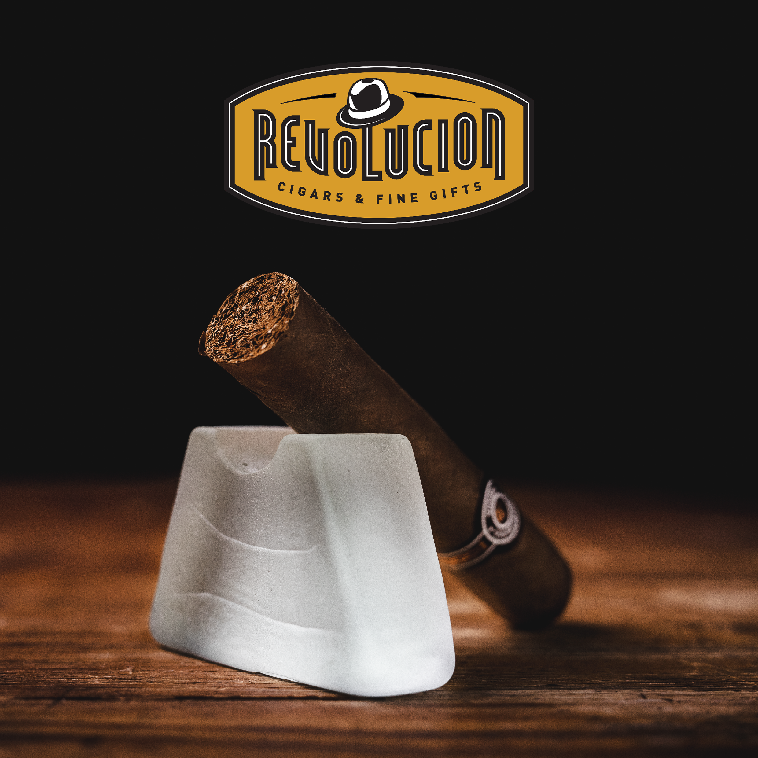 Montecristo Petit Edmundo Cuban cigar with a brown and white band, placed on a glass object with a dark background.