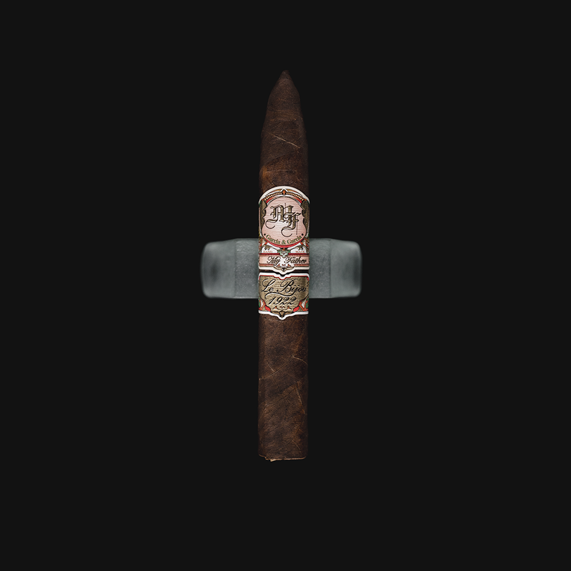 My Father Le Bijou 1922 Torpedo cigar with a dark oily wrapper, placed elegantly beside a cutter and glass of bourbon.