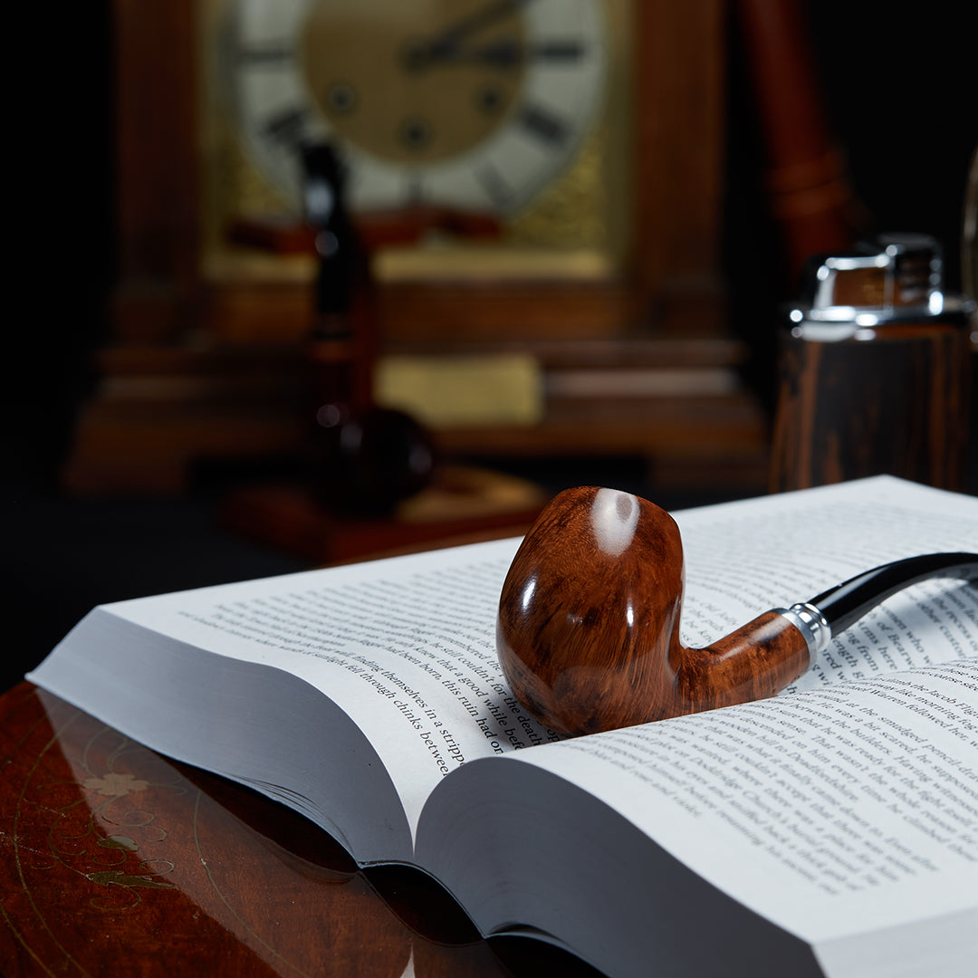 Nording Valhalla Spigot 504 Bent Billiard 9mm Smoking Pipe resting on a book, highlighting its elegant briar grain and silver spigot.