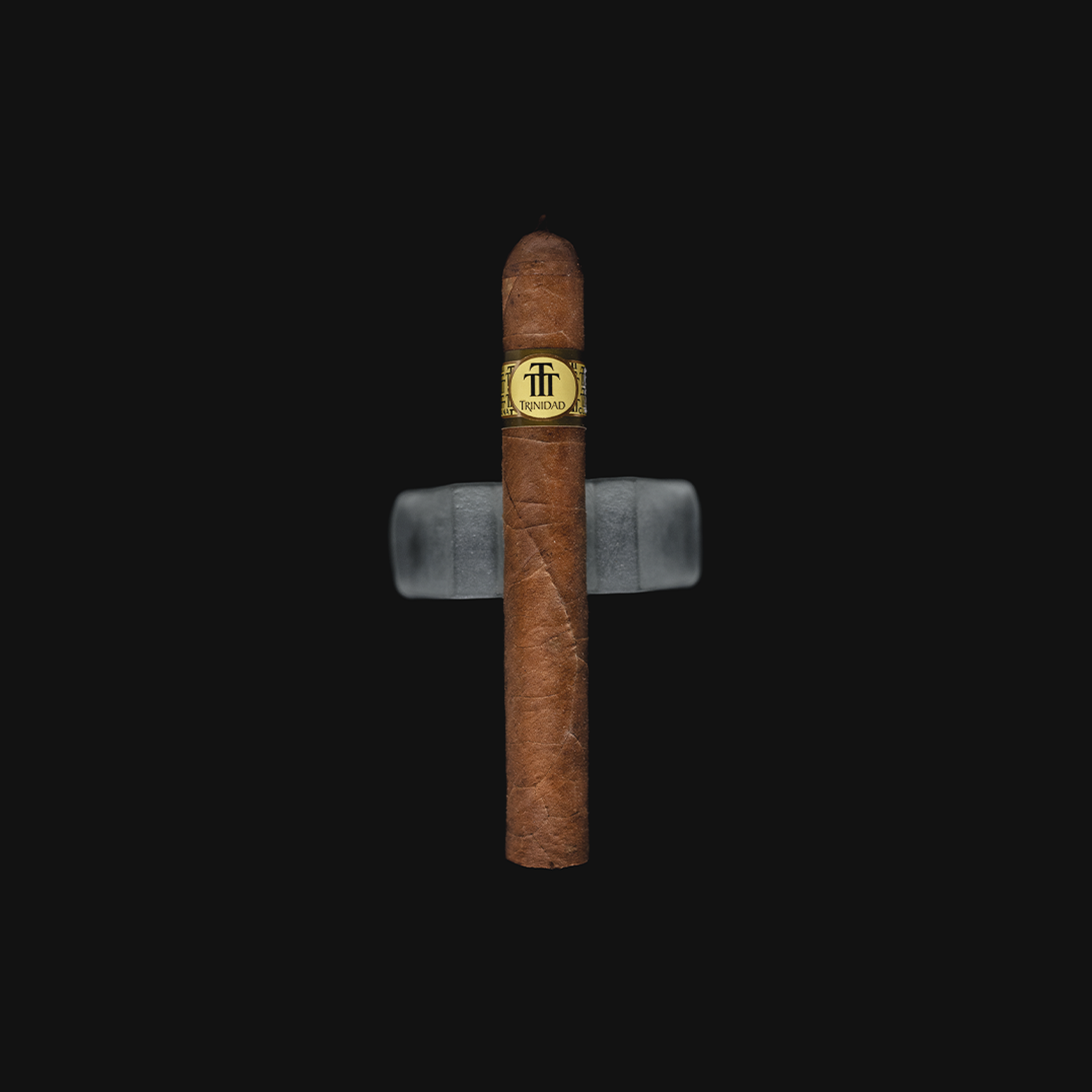 Trinidad Coloniales Cuban cigar resting on a dark background, showcasing its golden band and signature pigtail cap.